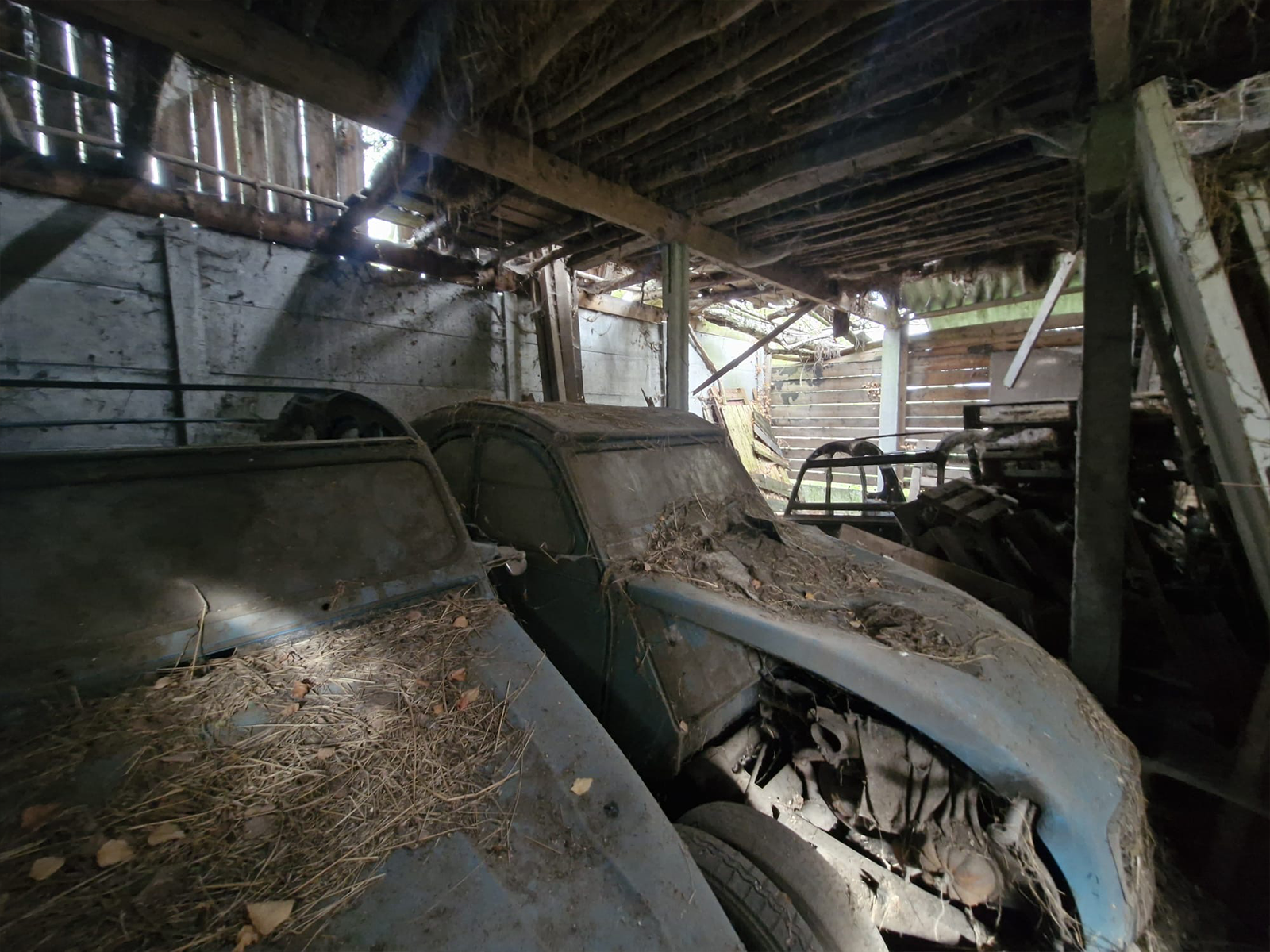 Detail van een stoffige klassieke Citroen eend in een donkere verlaten schuur